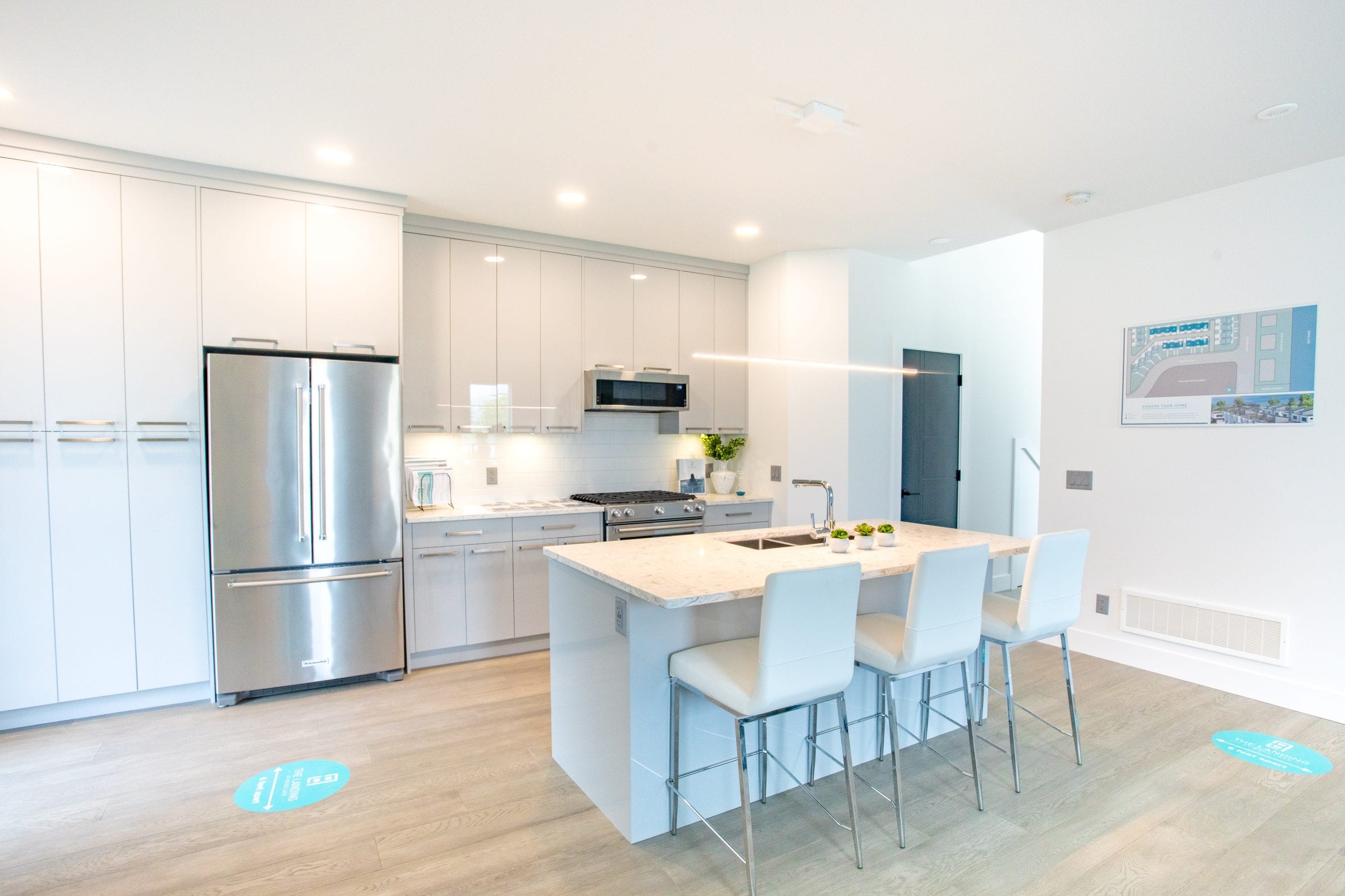 Sleek kitchen design with quartz, stainless KitchenAid appliances, high gloss cabinetry and hardwood floors.